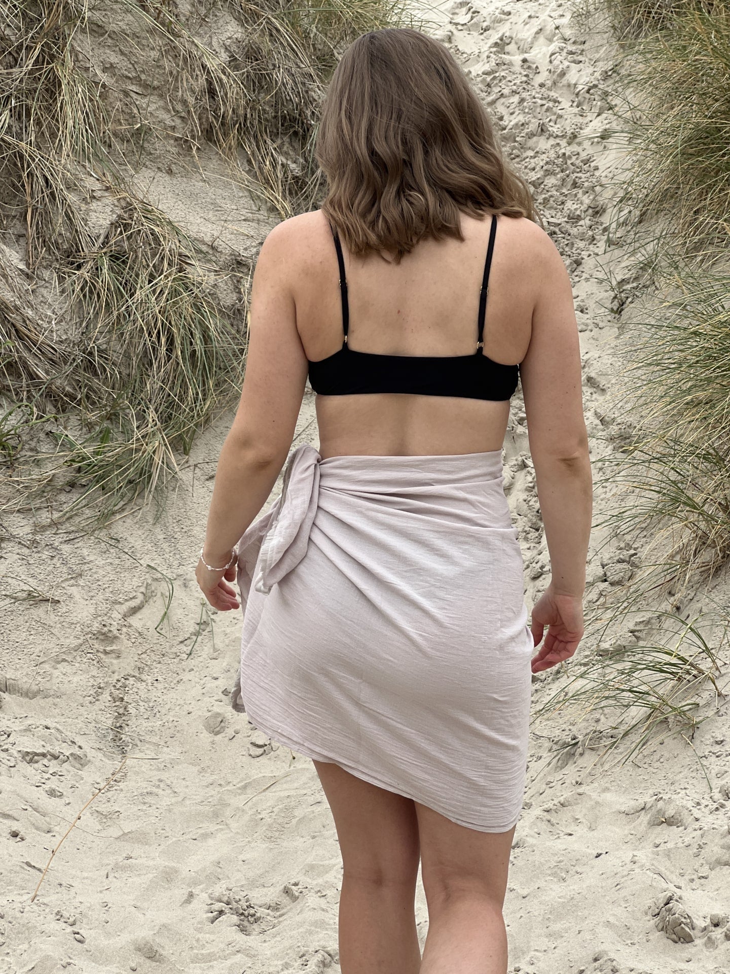 Kvinde gående på strand i champagnefarvet hørsarong