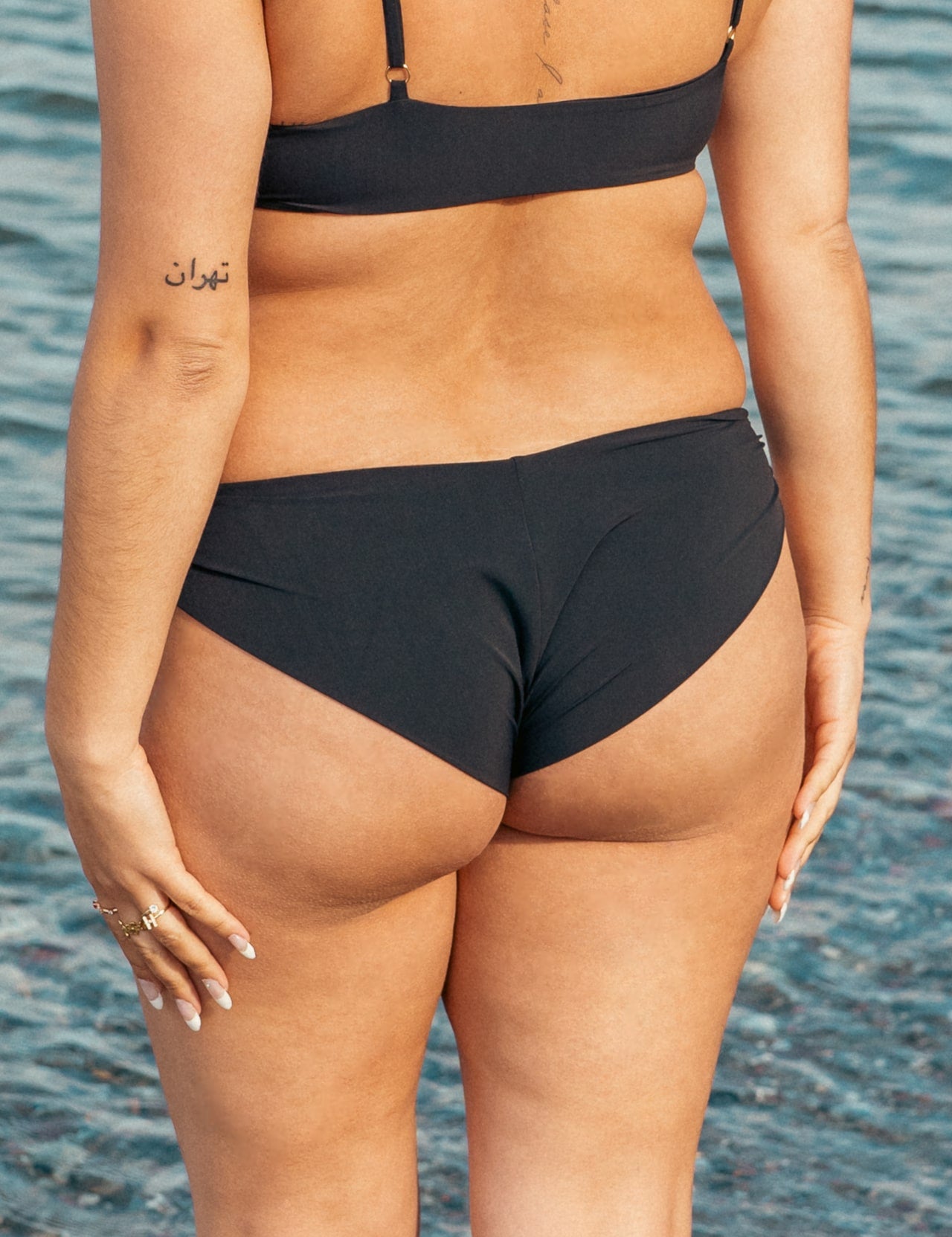 Kvinde i sort cheeky bikinibund på stranden