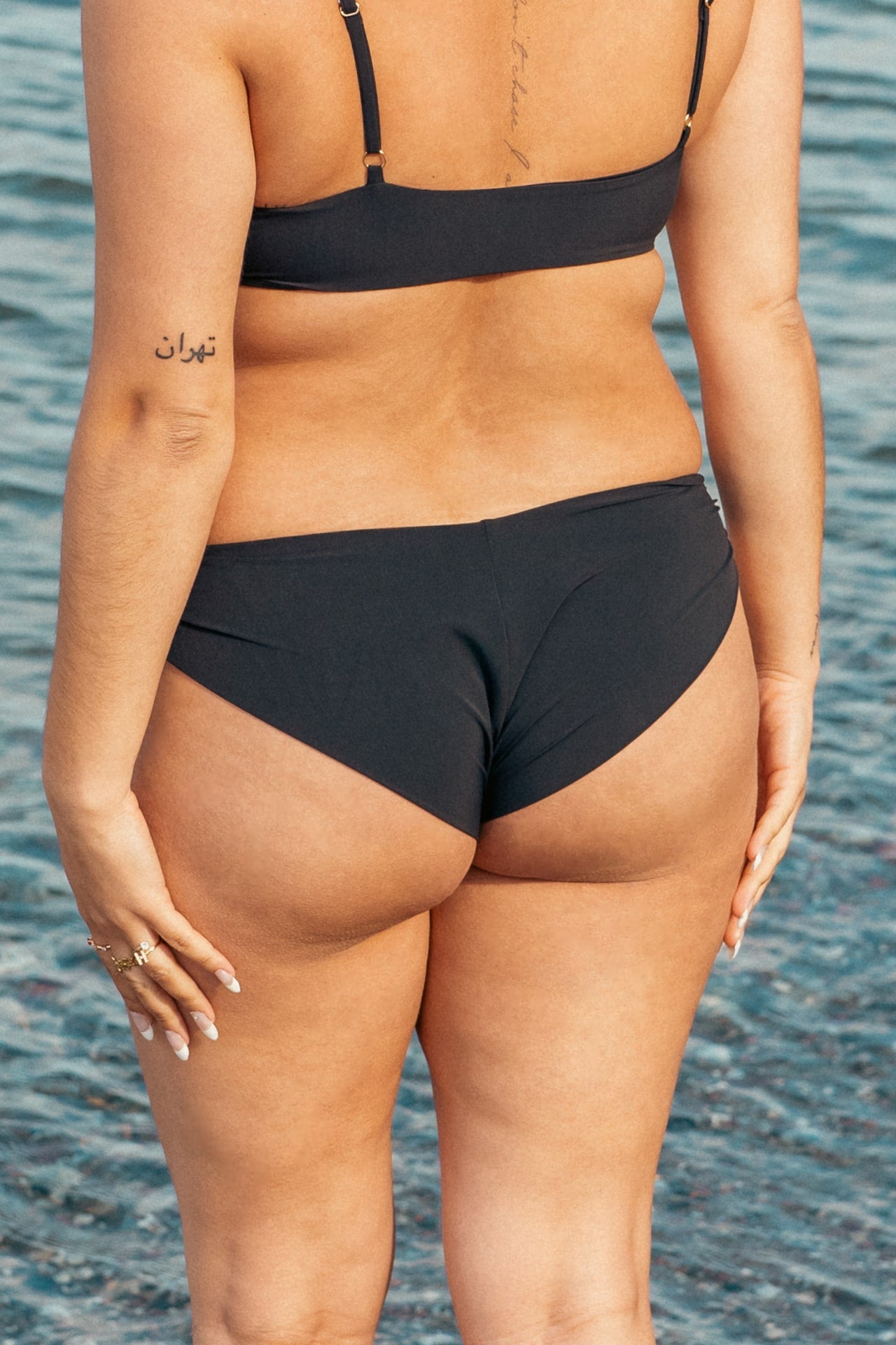 Kvinde i sort cheeky bikinibund på stranden