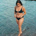 Kvinde i sort cheeky bikiniunderdel på stranden