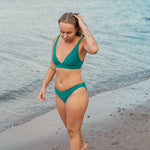 Kvinde i smuk grøn bikini på stranden til alle former