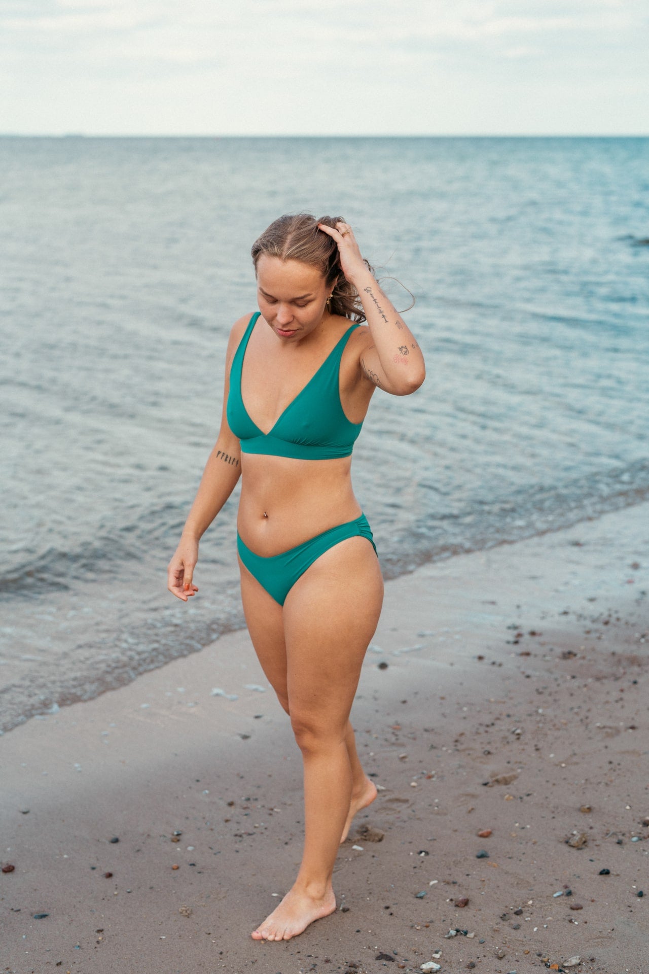 Kvinde i smuk grøn bikini på stranden til alle former