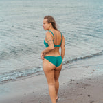 Kvinde i grøn bikiniunderdel på stranden