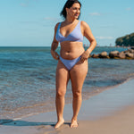 Kvinde i cheeky lilla bikini bund på stranden
