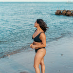 Kvinde i behagelig sort bikini på stranden