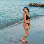 Smuk kvinde i sort brasiliensk bikini bund på strand